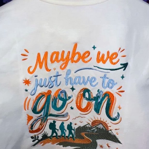 Hand-lettered embroidered artwork on a bone t-shirt reading